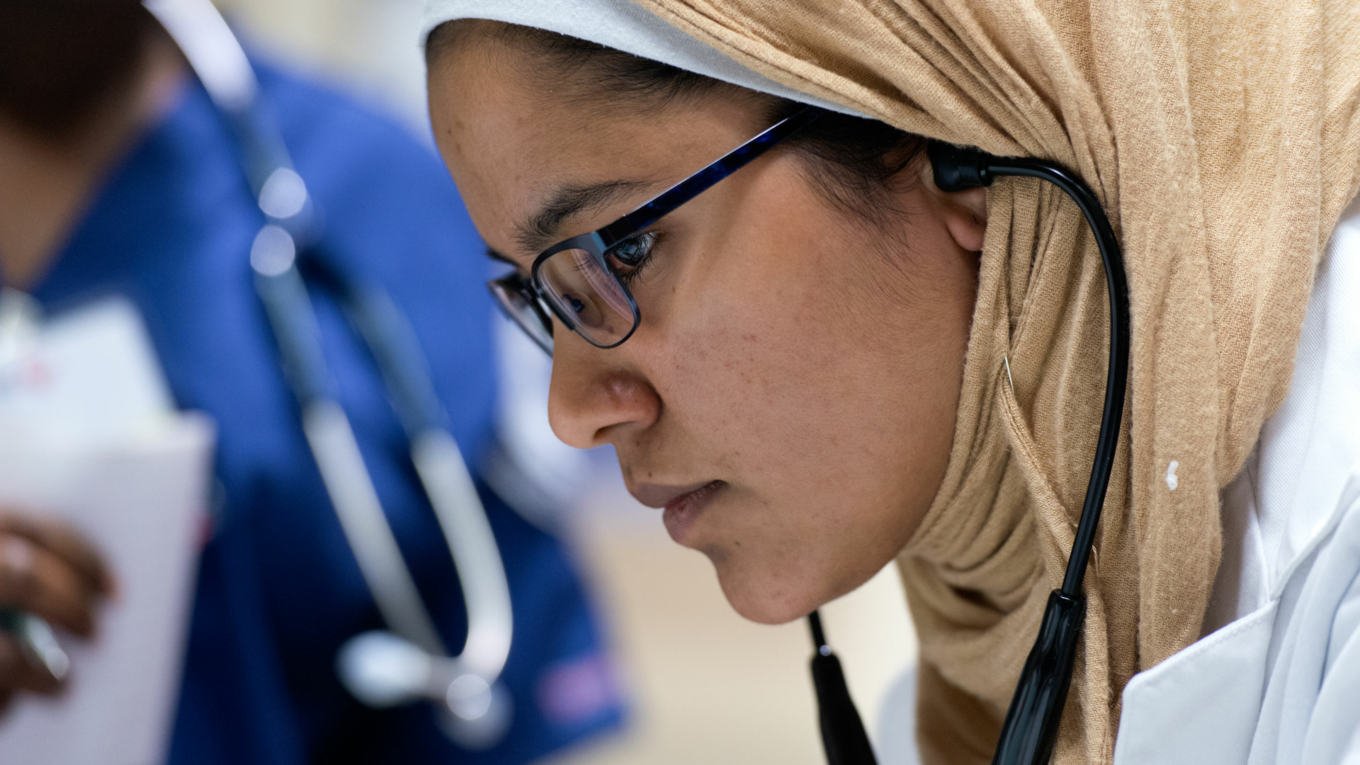 a nursing student looking at a patient with a stethoscope on