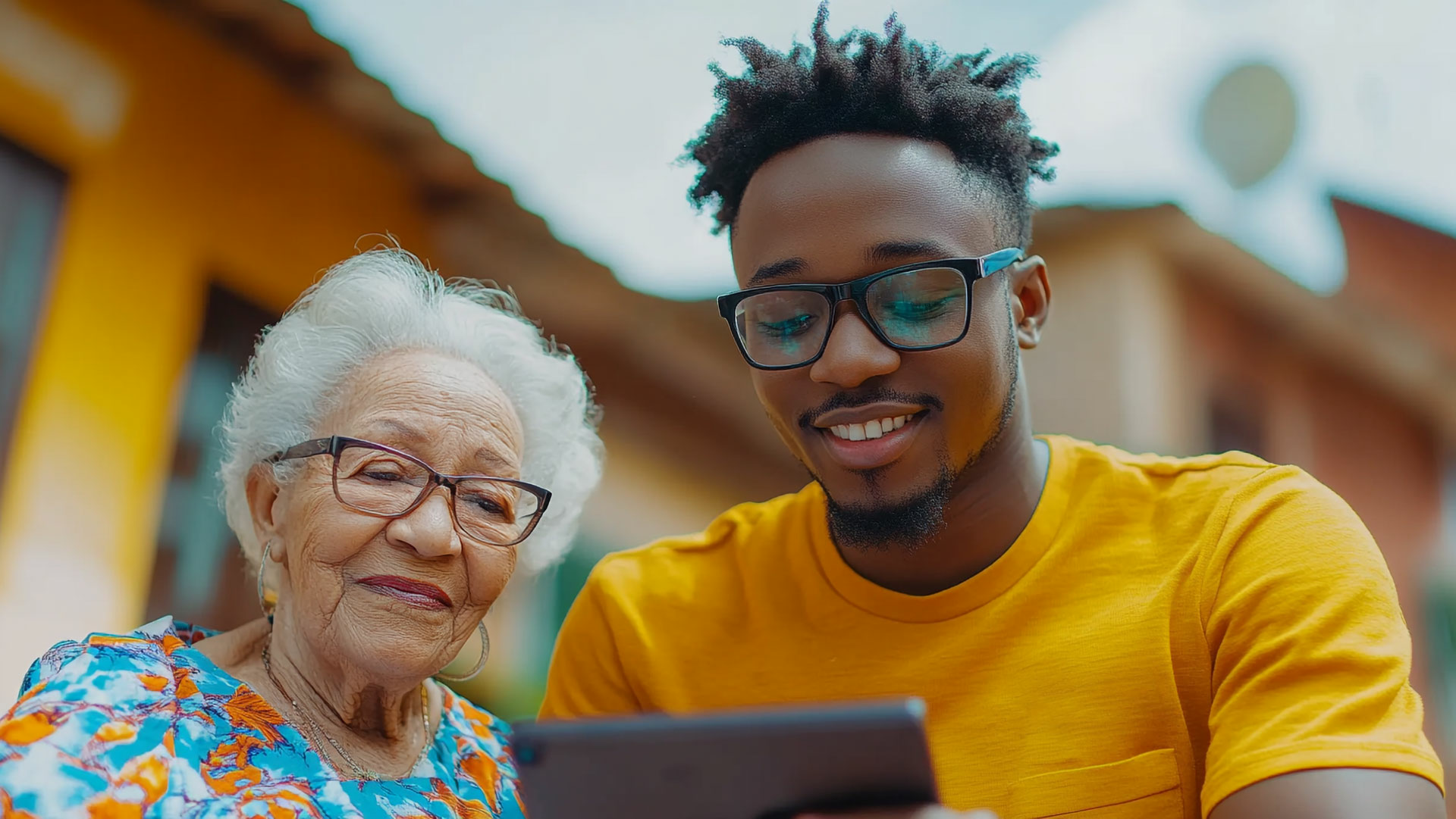 a young man showing an elderly woman how to use a tablet