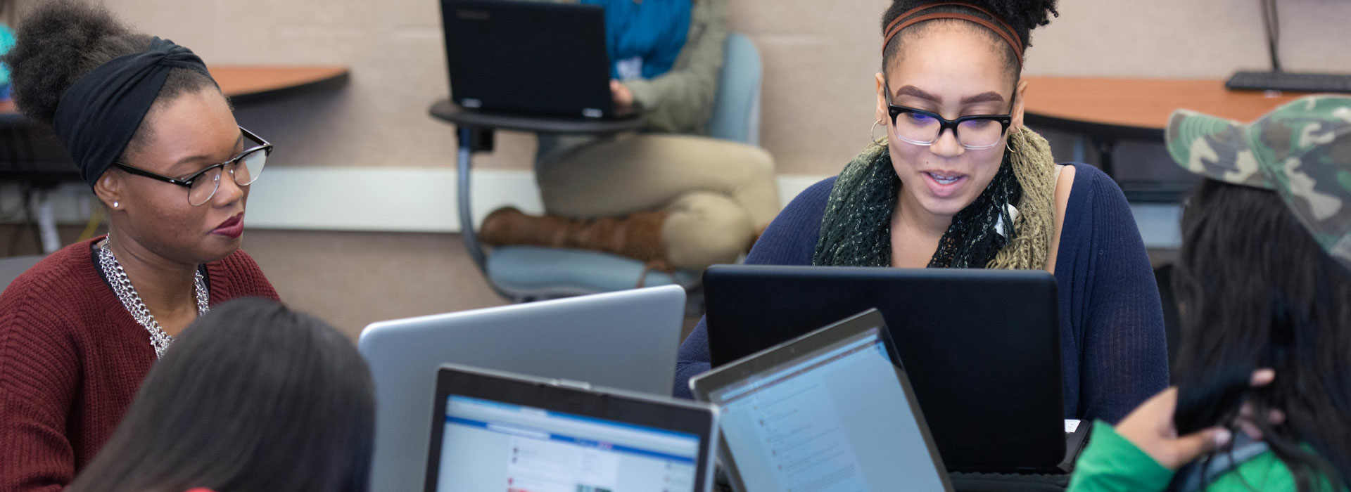  a group of women sitting in a circle with their laptops collaborating